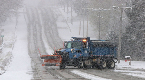A City of Sheboygan snow plow truck drives down a snowy street.